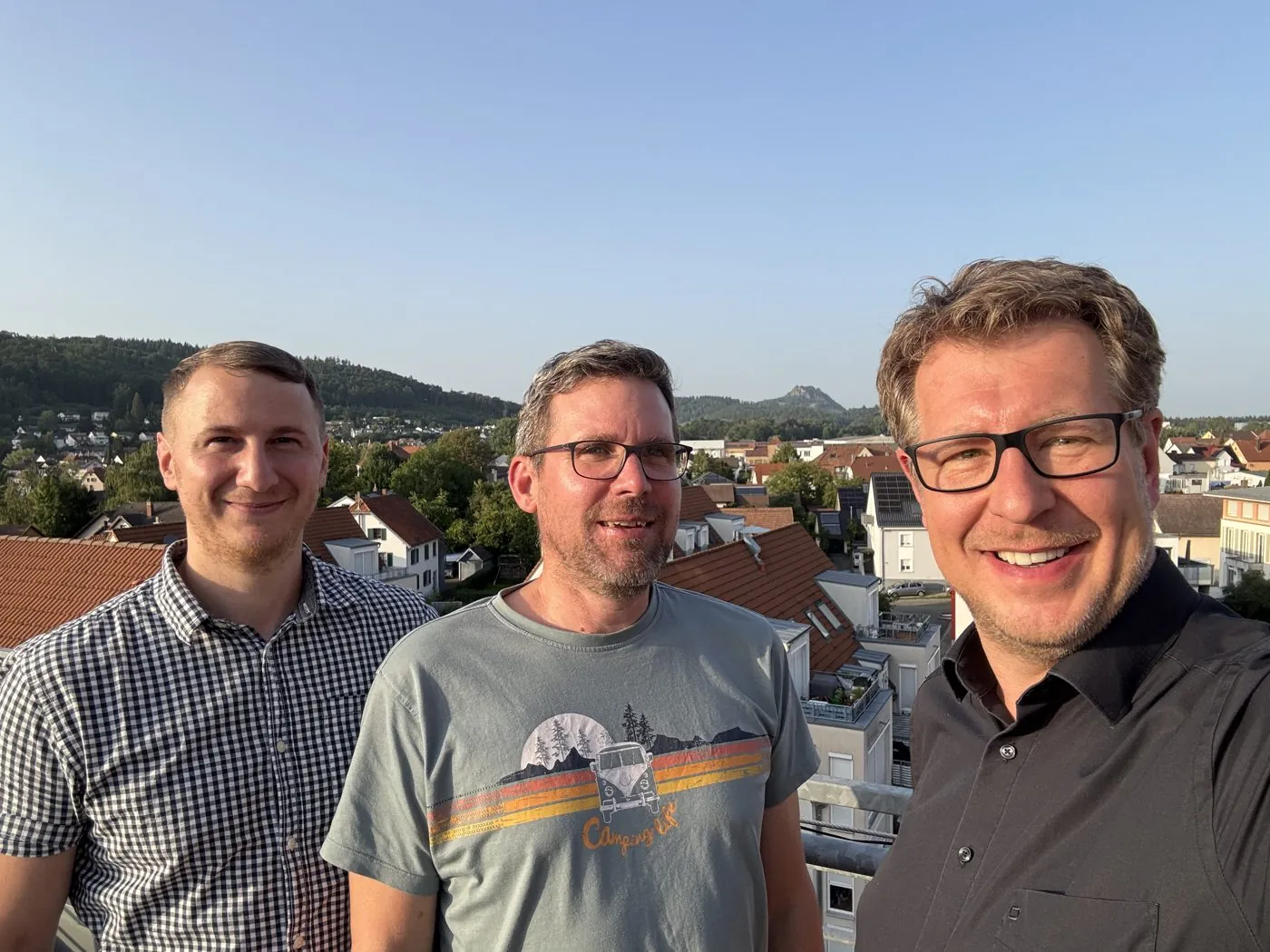 Gerd Bart mit zwei Kollegen auf einer Dachterrasse am Strategietag im August 2025